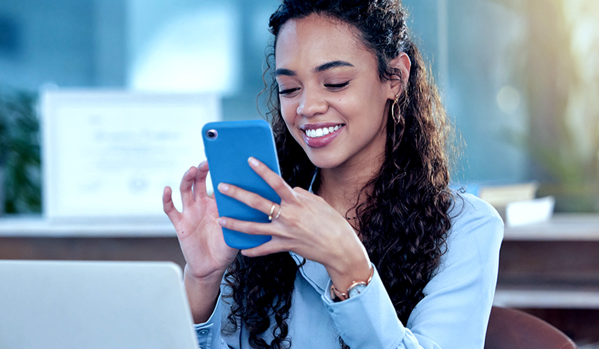 A woman smiling while looking at a mobile phone